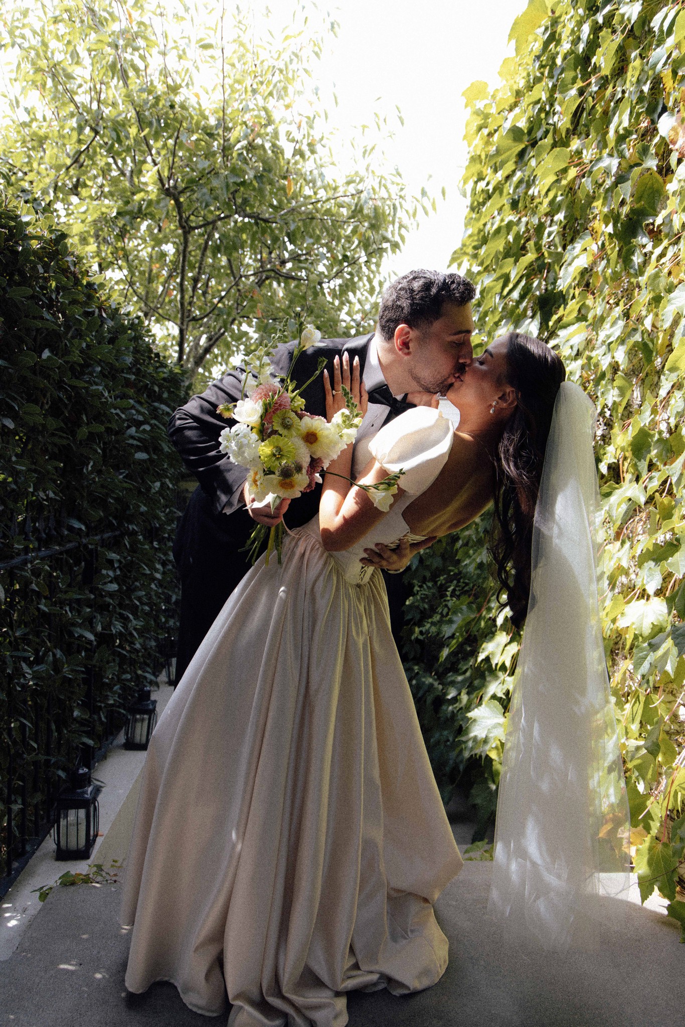 Bride and groom kissing in a garden path